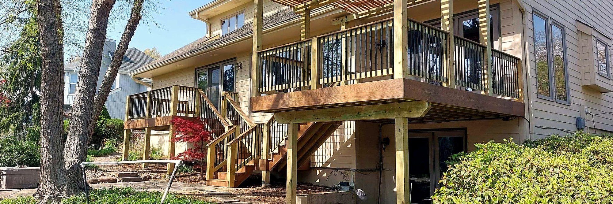 Deck with a pergola built out over a pond behind a home.