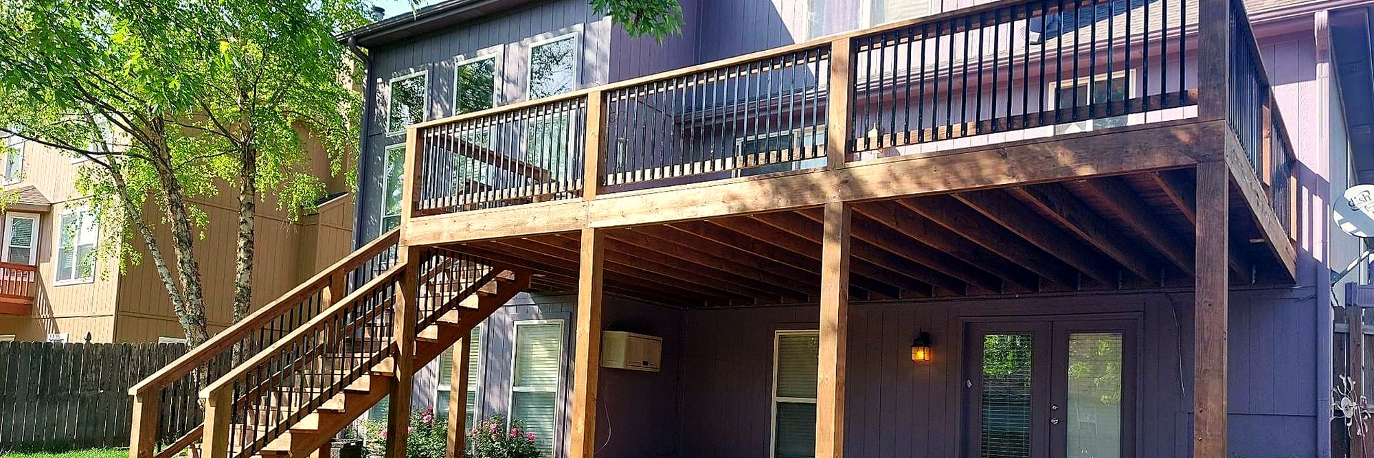 A two-story deck with a stair run behind a suburban home.