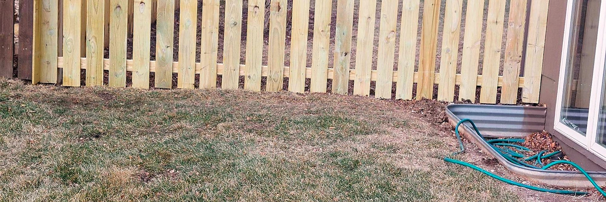 New cedar picket fence running along a residential property line.