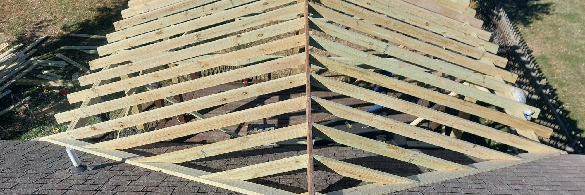 Hip roof framing going up over a new porch, seen from the roof of the house.