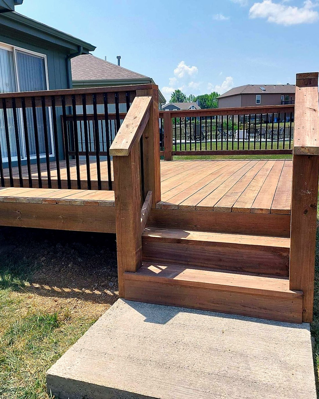 Cedar deck with black aluminum balusters and a wide stair landing.