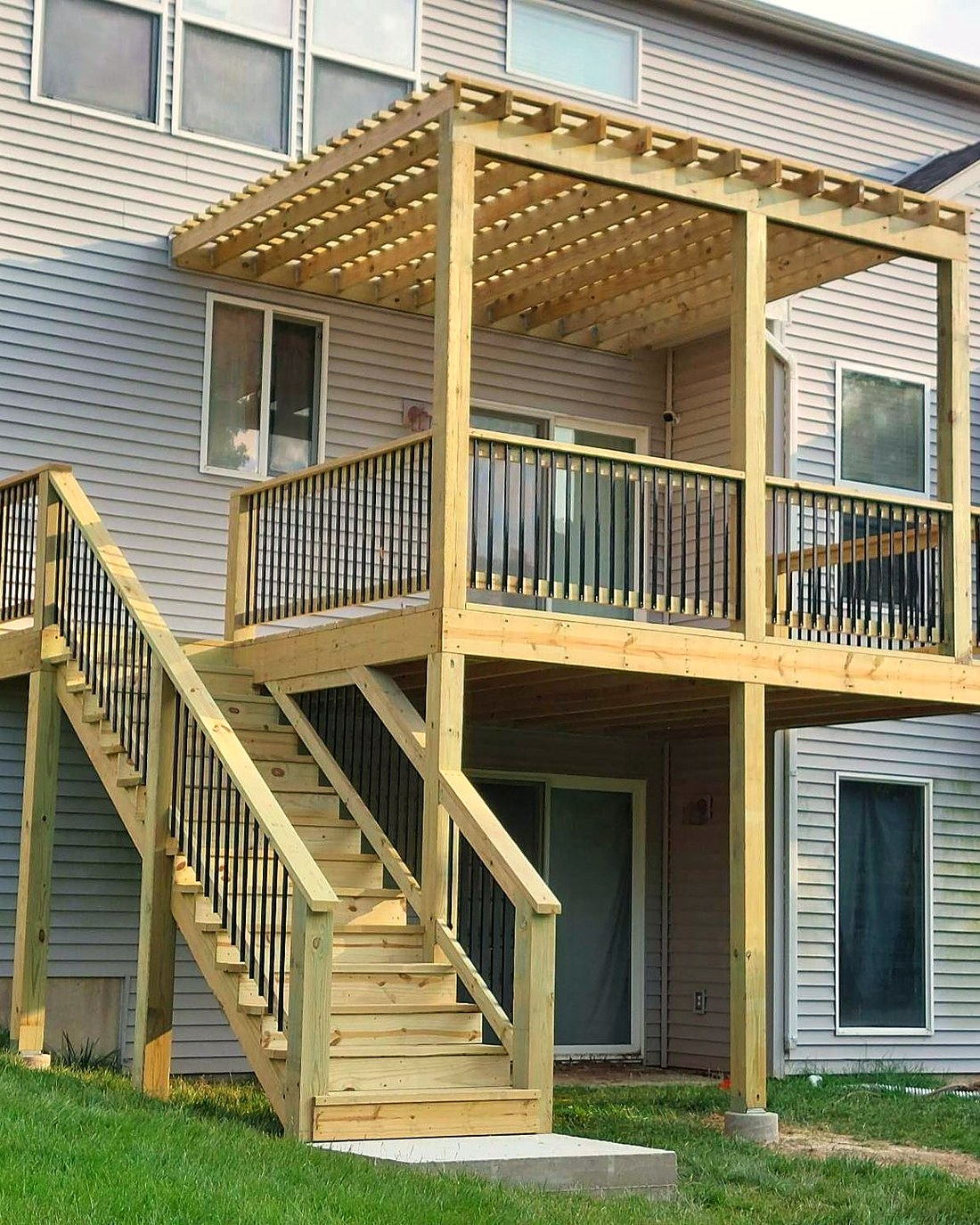 Timber pergola over the upper level of a deck, seen from the yard.