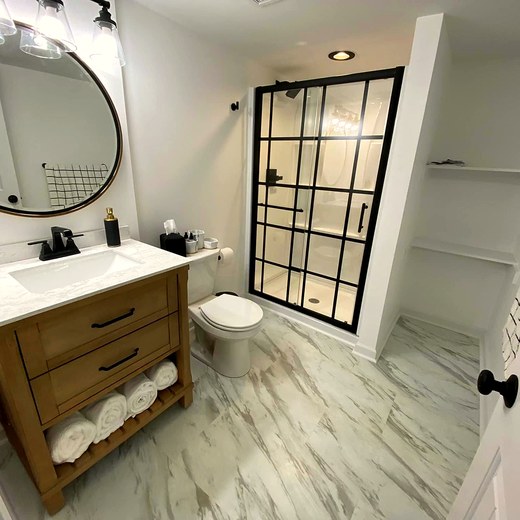 Finished bathroom with a glass shower and a round mirror.