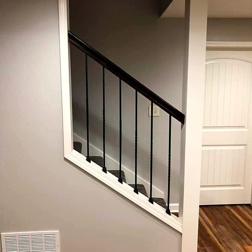 Finished basement stair with black metal balusters.