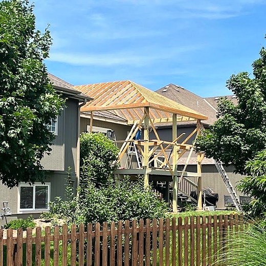 Roof framing going up over a screened porch structure.