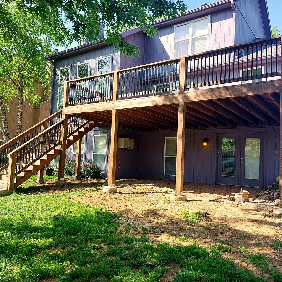 Large multi-level deck with stairs behind a two-story home.